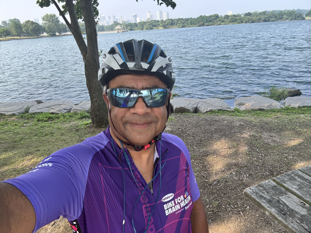Cyclist by the lakeshore with the city skyline behind